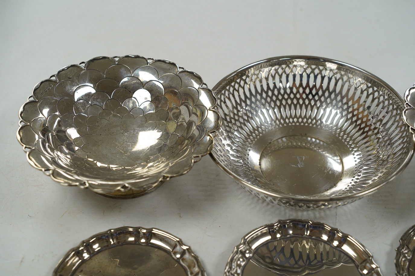 A pair of George V silver pedestal bonbon dishes, Birmingham, 1916, diameter 12.7cm, a set of four similar silver glass coasters, a silver bonbon bowl and a pair of Chinese white metal dishes with inset coin bases by Wan